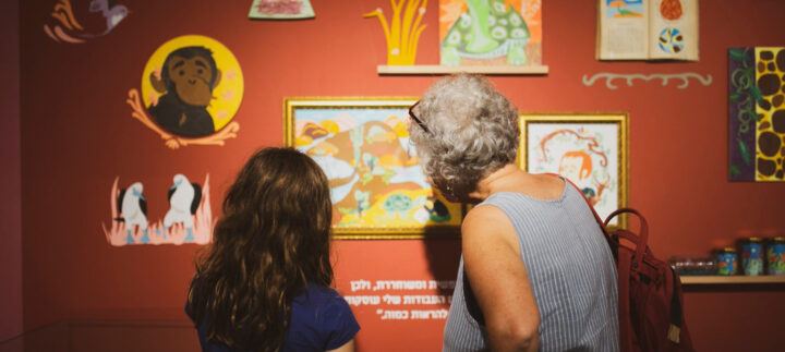 אישה וילדה מתבוננות בתמונה התלויה בתערוכה
